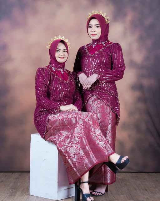 Dua perempuan memakai baju bodo modern warna maroon